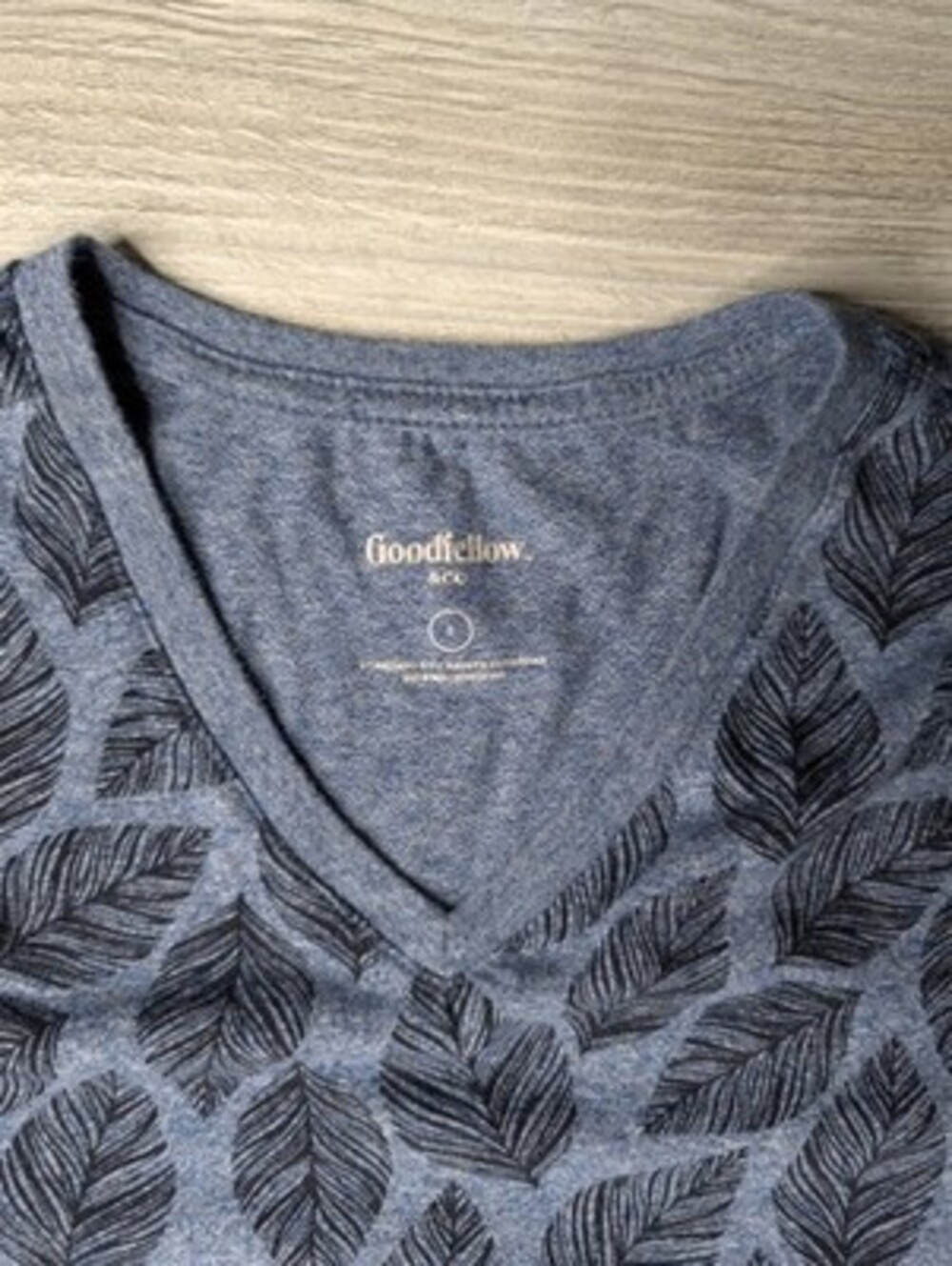 This blue Goodfellow & Co v-neck shirt features a dark leaf pattern.